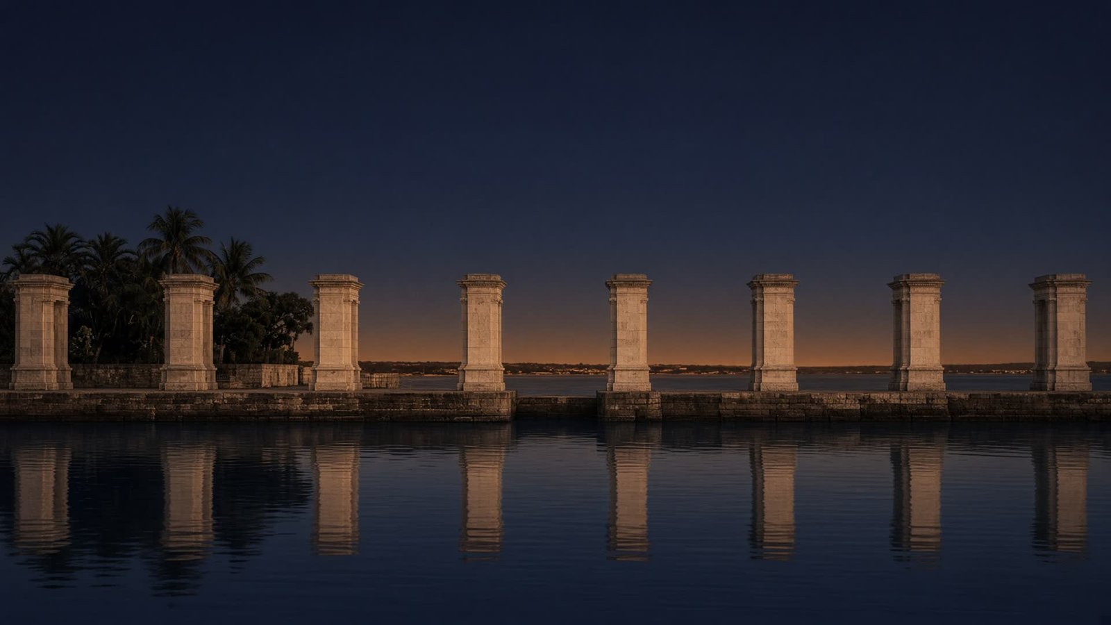 Stone quay and colonnade reflected in still harbour water at dusk