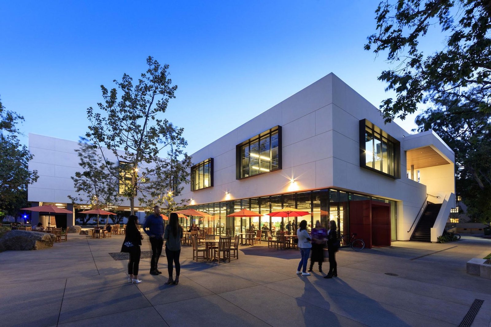 University campus building at dusk, courtyard and glass rooms lit from within