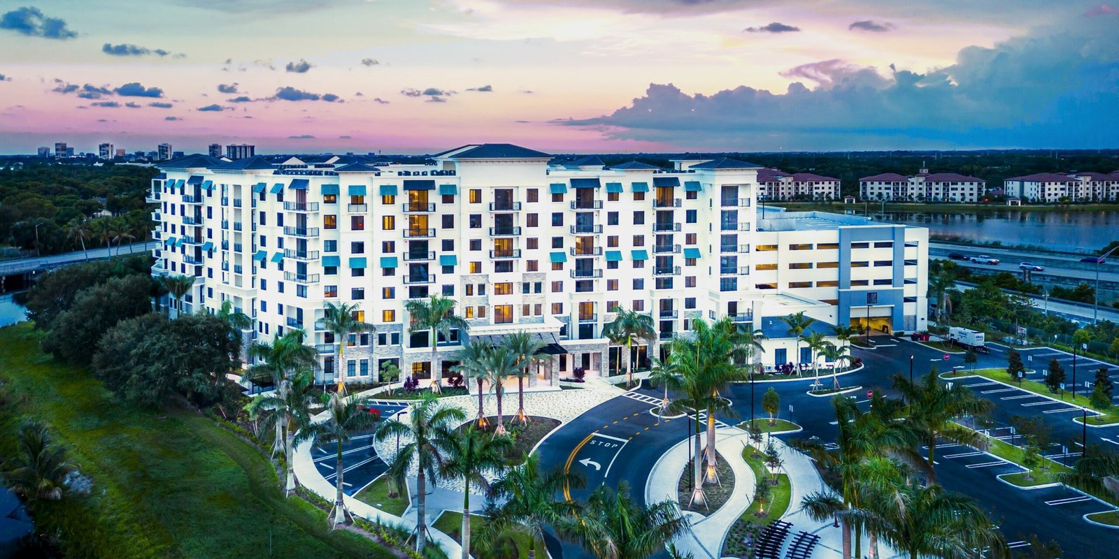 Residential apartment building at dusk, palms along a circular drive